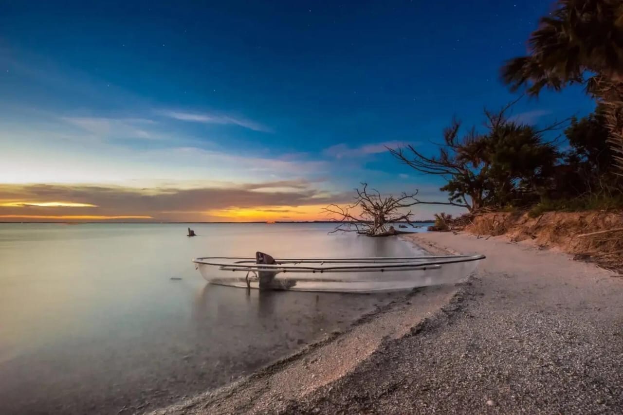 Merritt Island National Wildlife Refuge at twilight: Indian River with kayak on shore, silhouette of dead tree, palm fronds, deep blue starlit sky